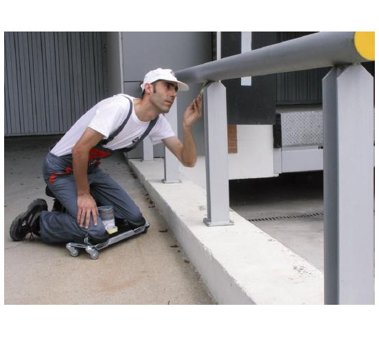 Siège ergonomique SR-1 RUBI en situation, carreleur à genoux sur l'outil, peignant une barrière.