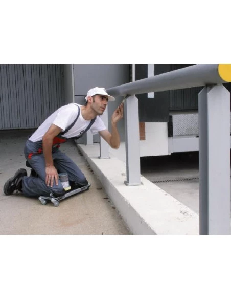 Siège ergonomique SR-1 RUBI en situation, carreleur à genoux sur l'outil, peignant une barrière.